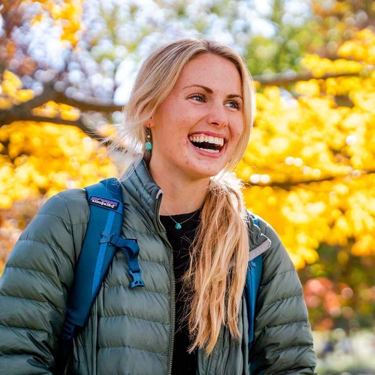 Smiling woman in professional attire smiles in a business park setting. 